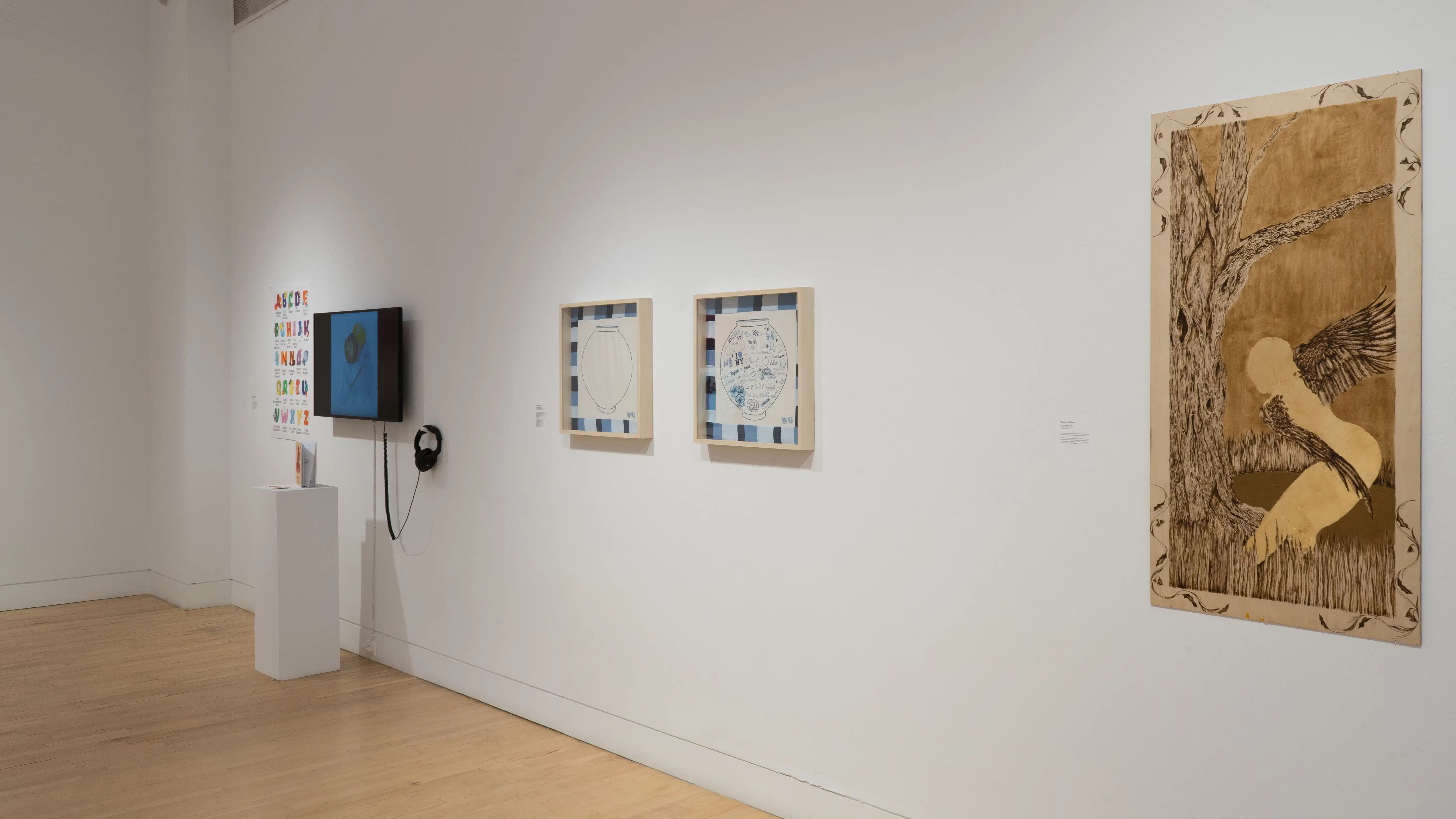  Angled shot of the east wall at the SVA Flatiron Gallery, showing a monochrome painting on wood panel in the foreground, two framed square drawings of pots, and a monitor in the background. 