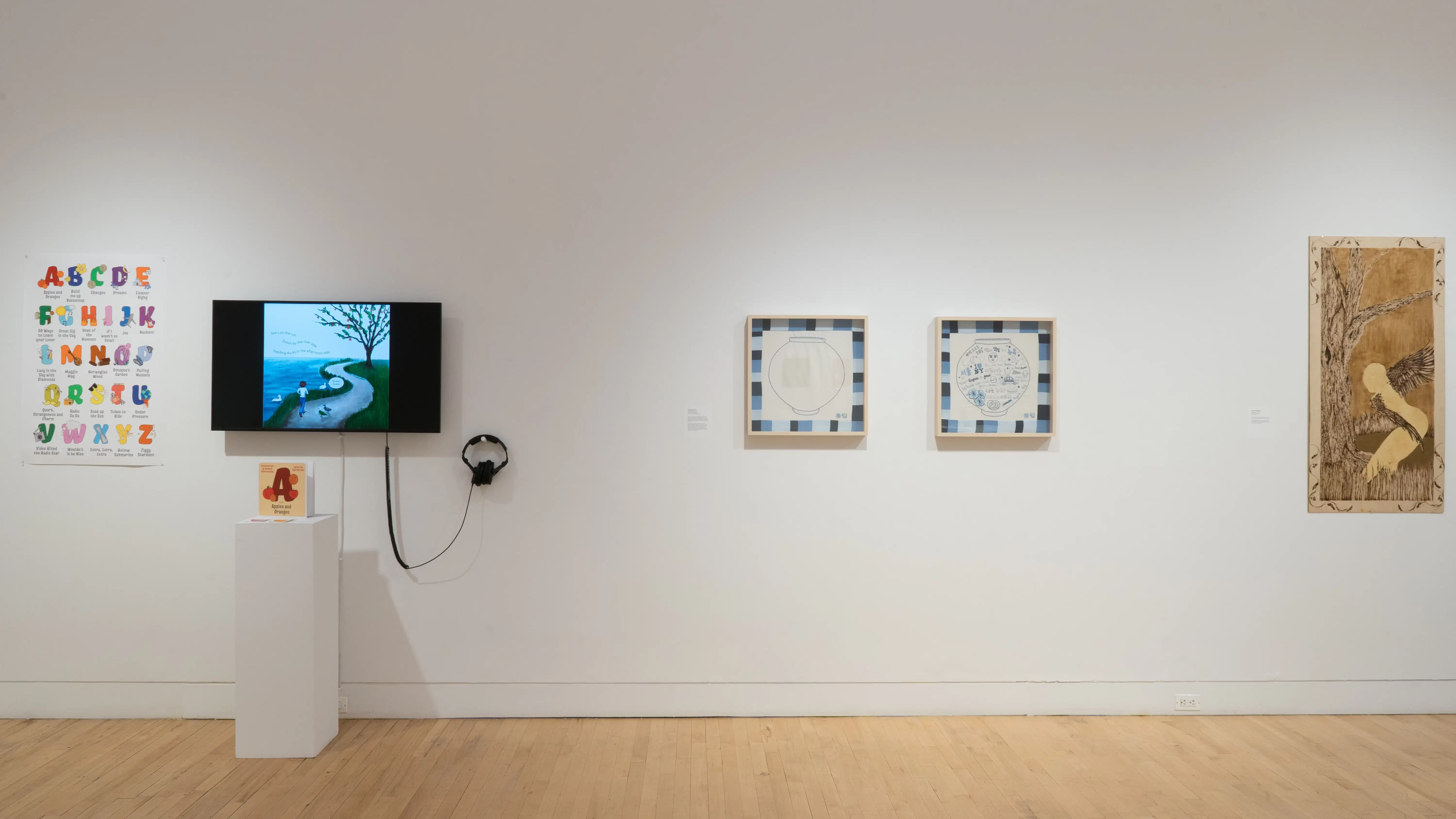 Straight shot of the east wall at the SVA Flatiron Gallery, showing a monochrome painting on wood panel on the right, two framed square drawings of pots in the center, and a monitor on the left. 