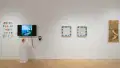  Straight shot of the east wall at the SVA Flatiron Gallery, showing a monochrome painting on wood panel on the right, two framed square drawings of pots in the center, and a monitor on the left. 