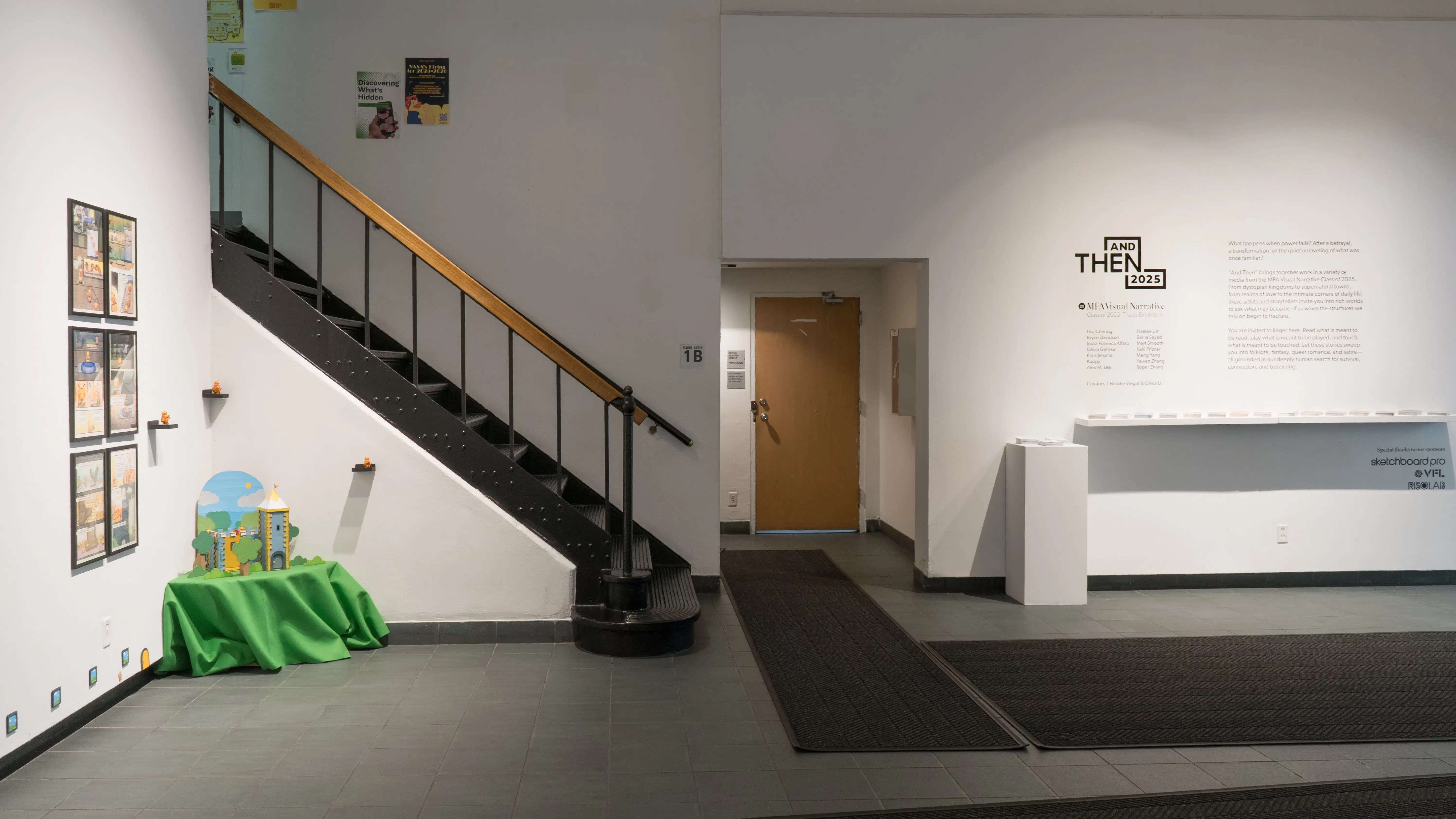 Another angle of the entrance to the Gramercy Gallery. On the left is framed art, next to a small diorama of a castle in a forest. On the wall facing the camera is the title and description of the exhibition.