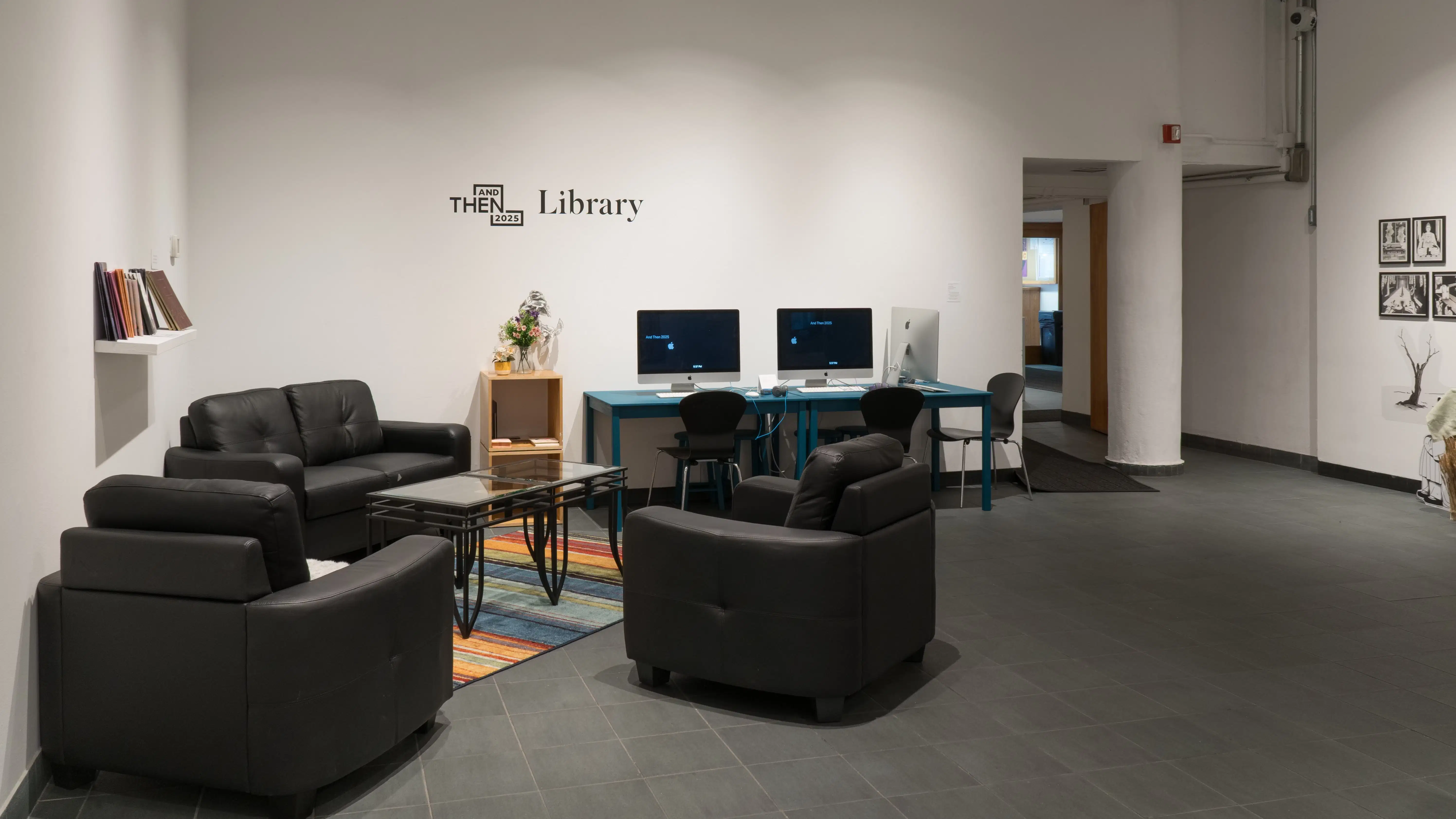 Three black leather chairs facing each other. On the left, a shelf full of books sits on the wall, and behind the couches is a vase of flowers. A table with three laptops and three chairs sits next to the flowers.
