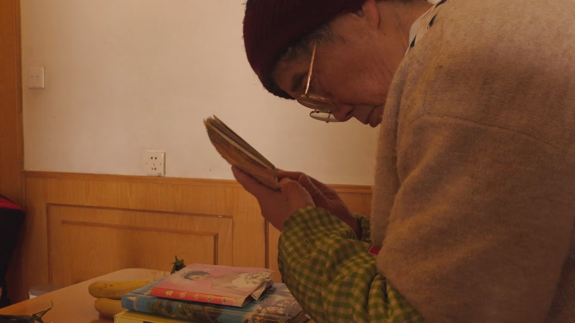 woman in glasses holds photographs close to face