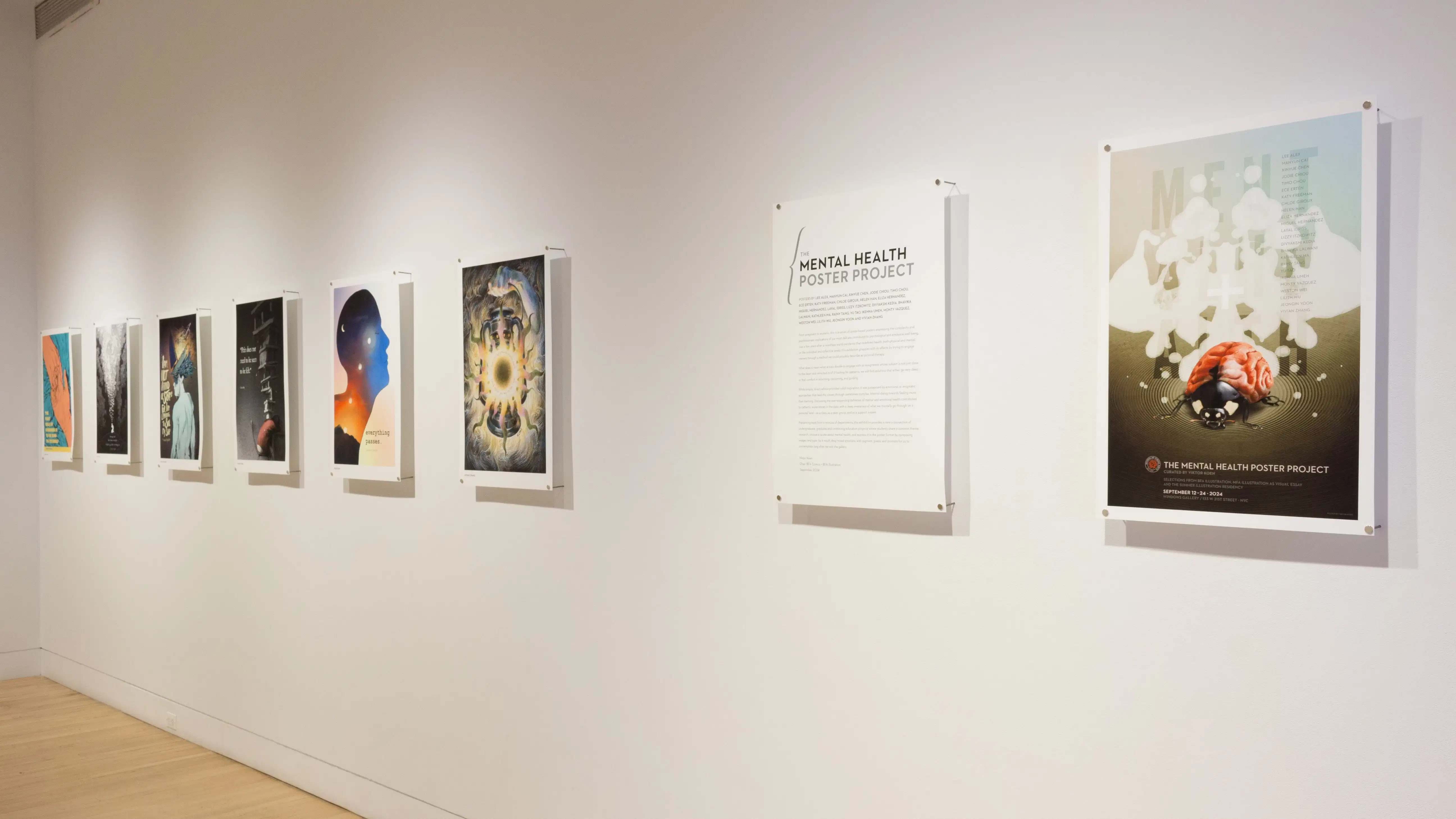 Poster sized illustrations hang in a line on the wall. There is text on one poster that reads  “Mental Health Poster Project.” 