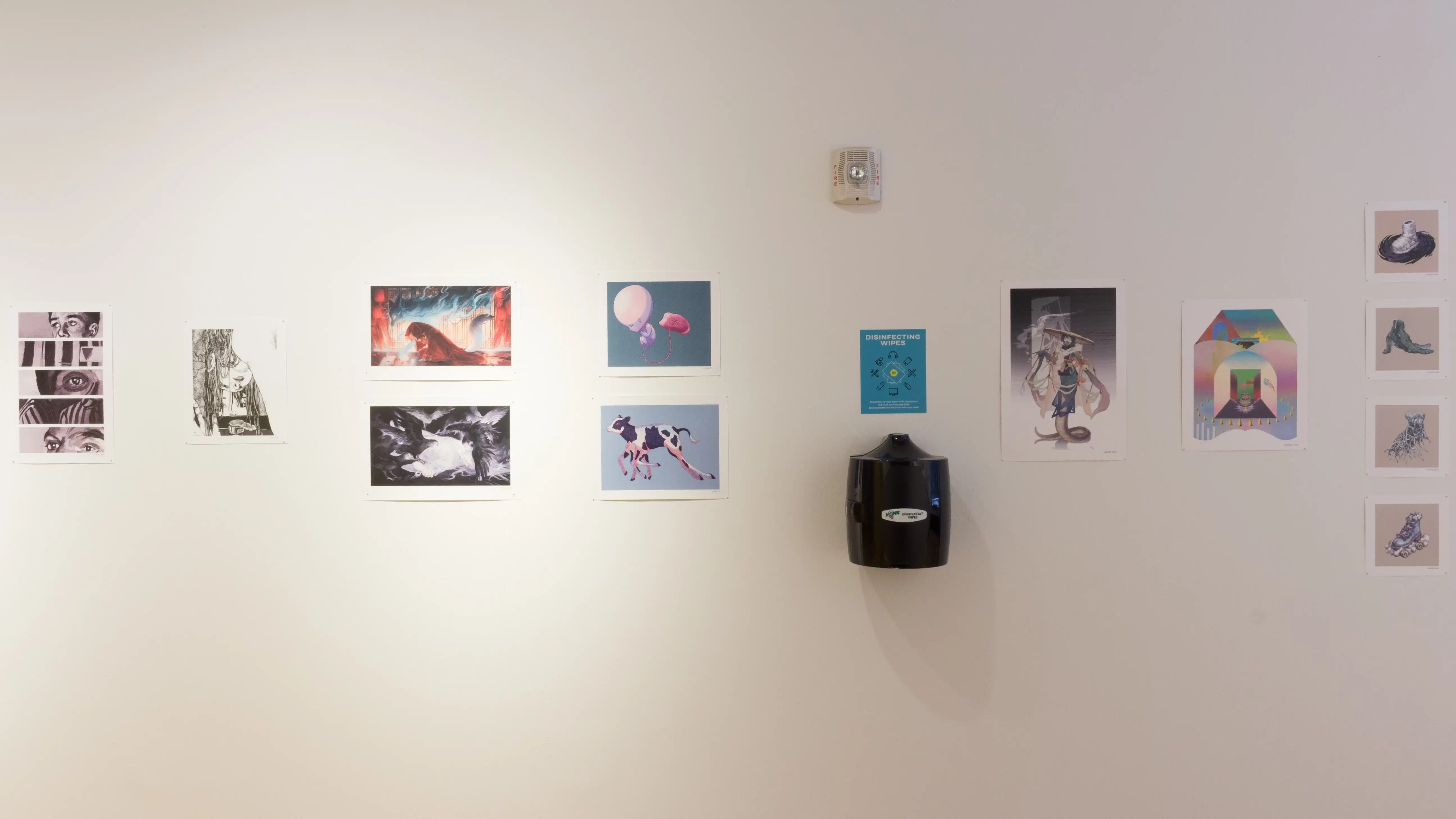 Eight illustrative posters hang along the gallery wall and four smaller illustrations are arranged in a vertical series.