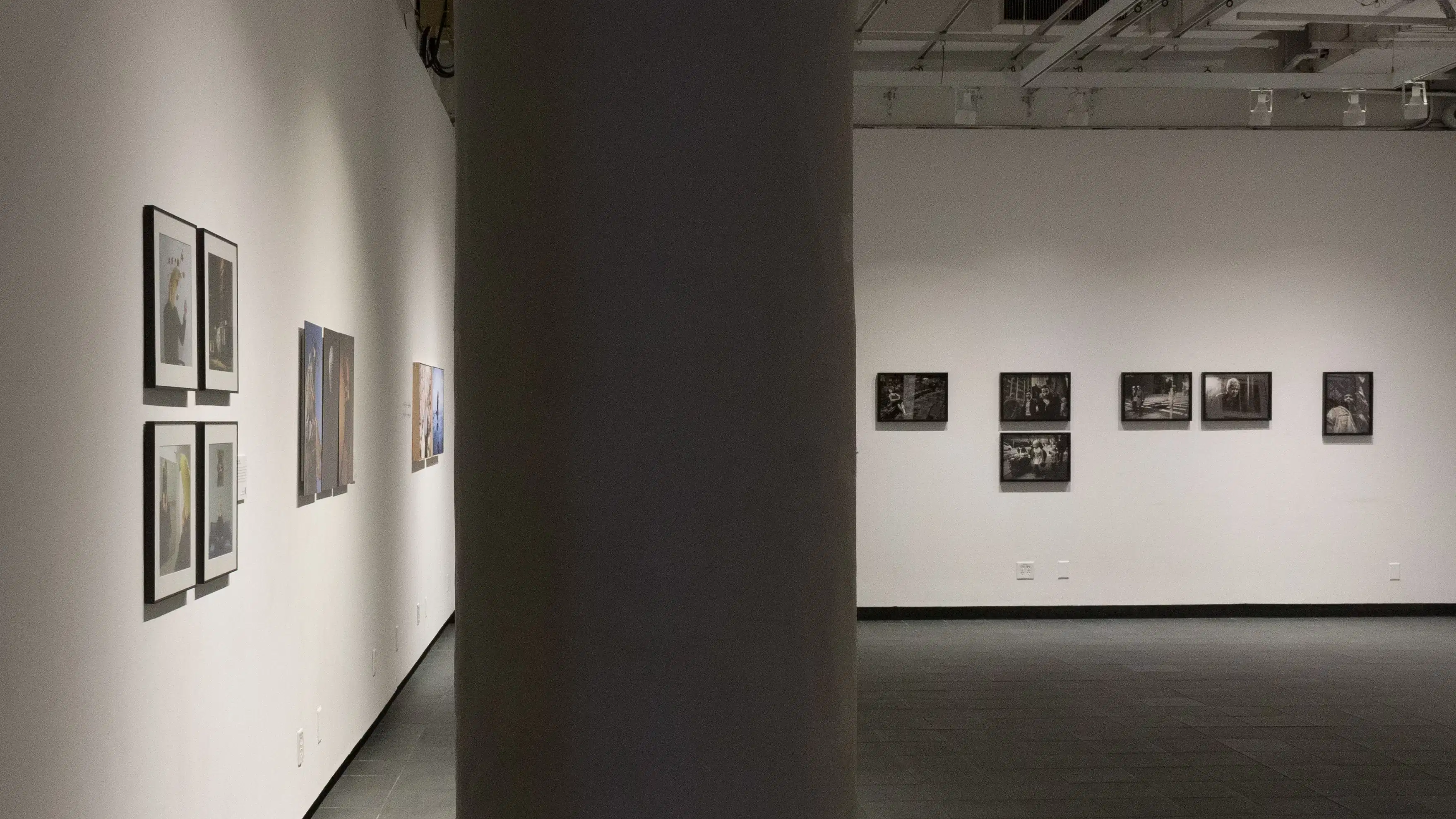 A series of black and white photographs hang on the back wall of the gallery.