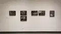 A series of black and white photographs hang on a wall of the gallery.