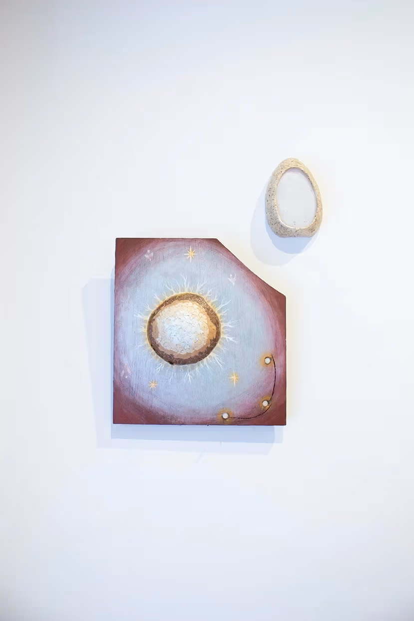 INstallation shot of a small sqaure painting with a corner cut out and an egg shaped ceramic piece on the top right.