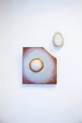 INstallation shot of a small sqaure painting with a corner cut out and an egg shaped ceramic piece on the top right.