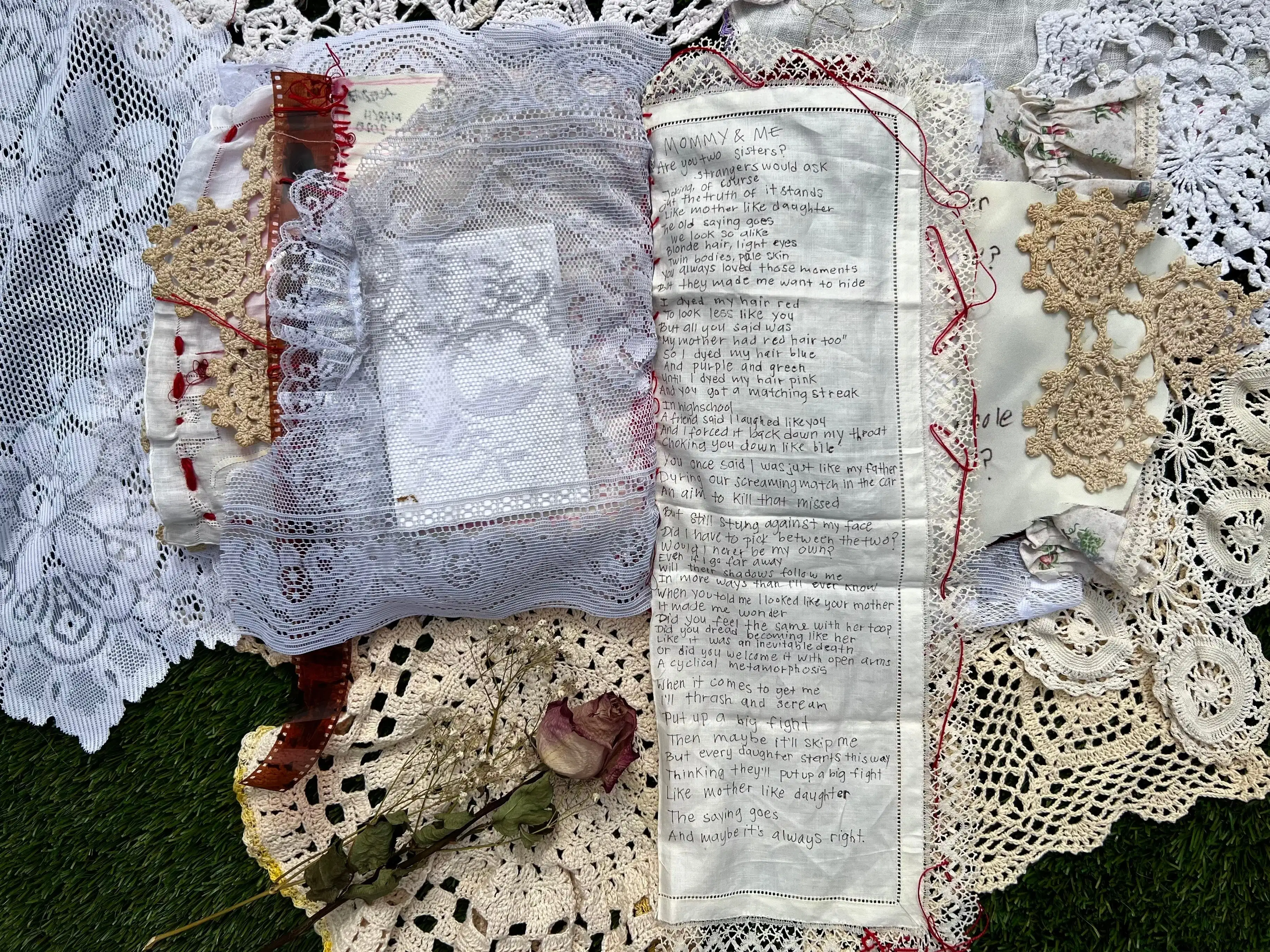 Page 11. On the left side gray lace covers the back of a photograph. A dried rose lies just below this page. The right page consists of a long narrative with title MOMMY & ME handwritten on piece of linen that folds out. Lace with long red stitches boarders this page.