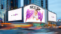 A wide shot of the side of a tall building in a modern looking city at dusk. The billboards are digital screens showing a Nike swoosh “Just Do It” ad with a woman in athletic attire jumping through the screen with the words “NICE TO BEAT YOU” displayed in colorful, purple, gooey looking letters. 