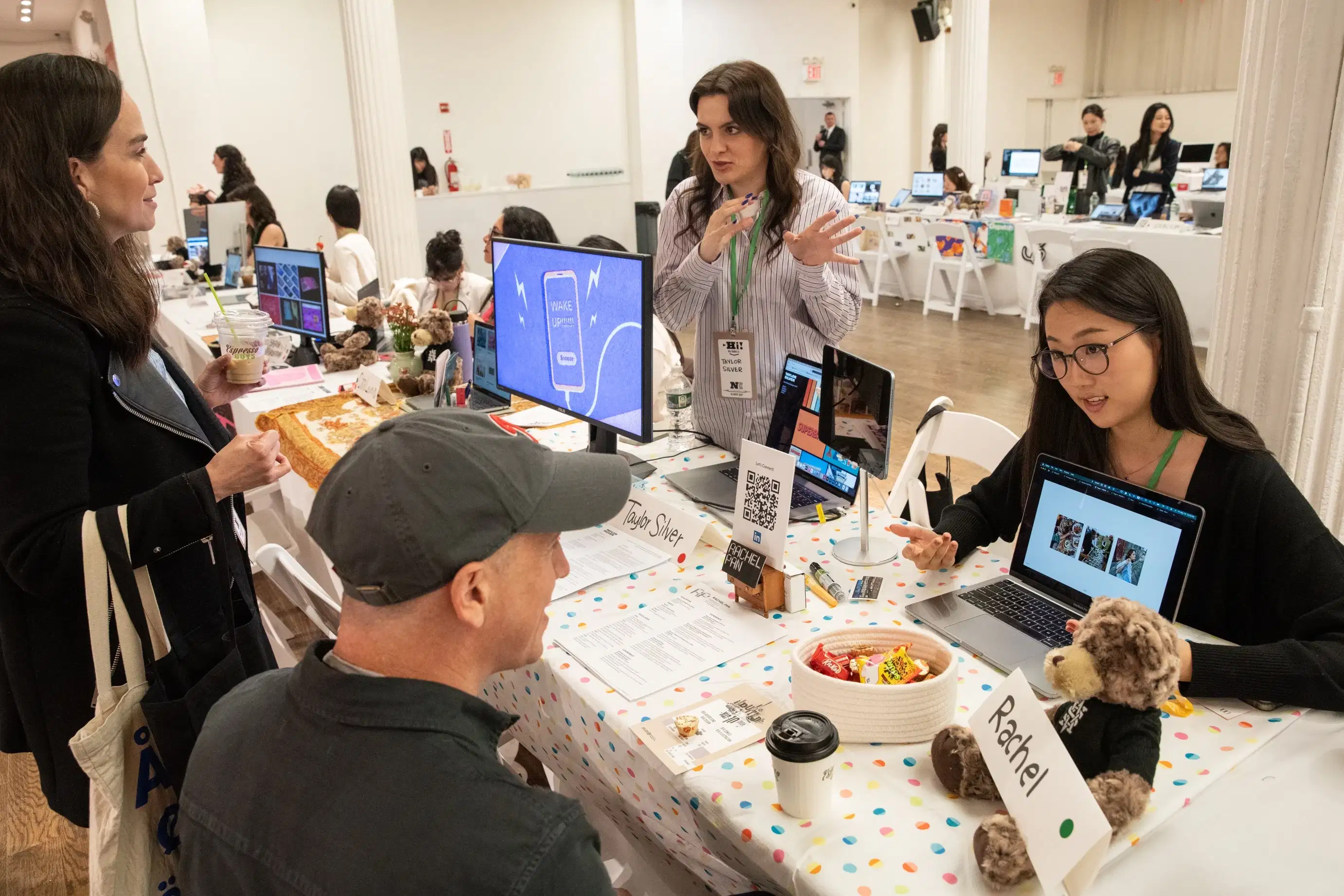 Two students chat with guests about their display of work.