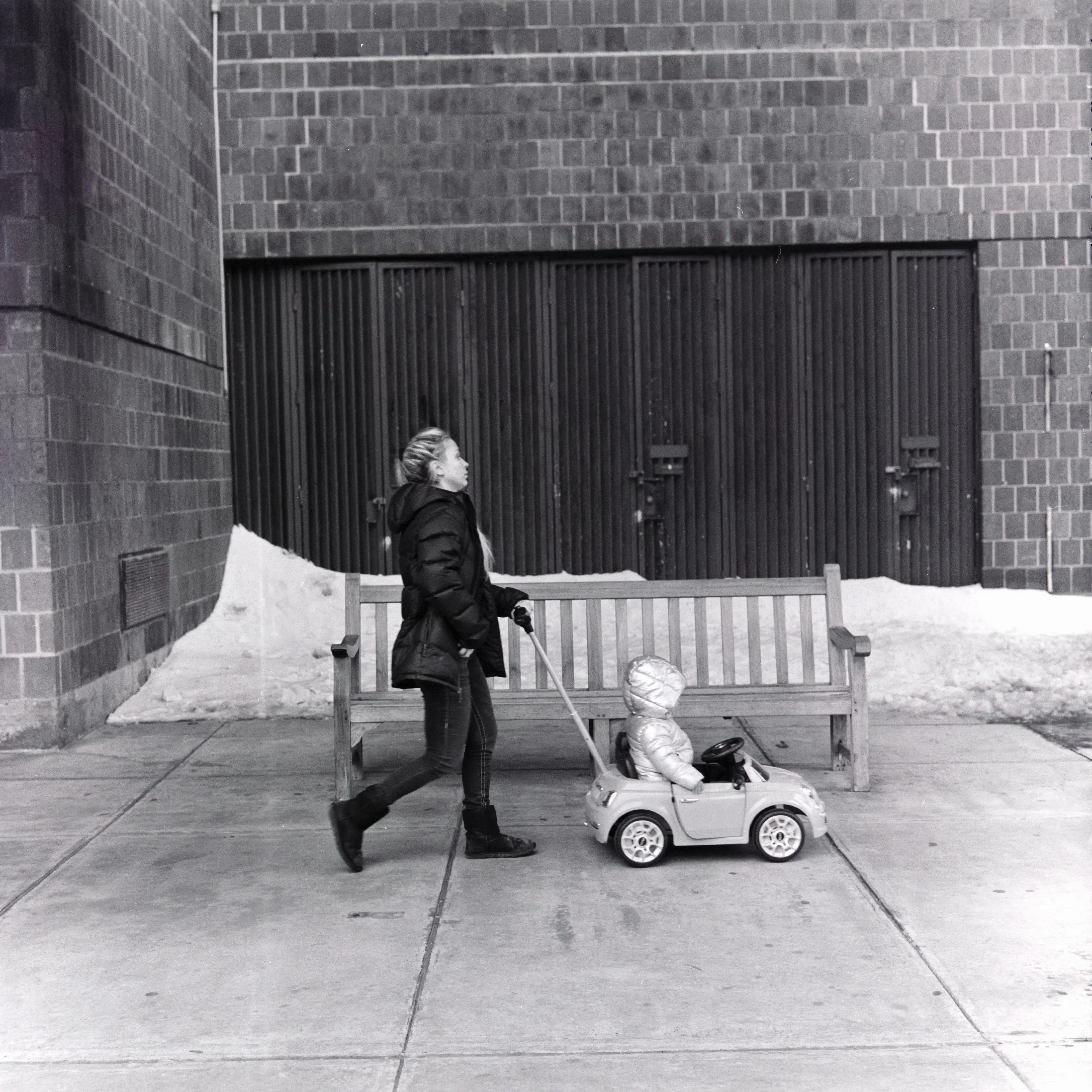 In the winter of New York, everything seems to slow down. The brick walls, benches, and lingering snow in the background add a touch of urban chill to the scene, yet they cannot mask the warmth of familial love. On the quiet streets, it feels as if only their story remains, gently pulling time forward.