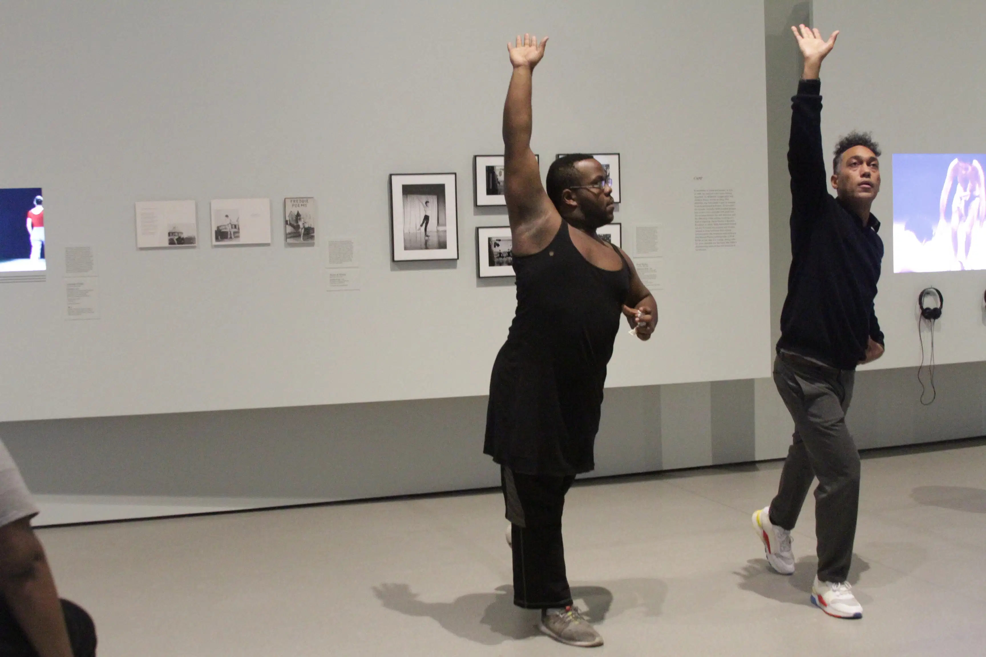 <p "="">Two people stand next to each other, their actions mirroring each other—right foot in front and right arm raised, with palm upward.
