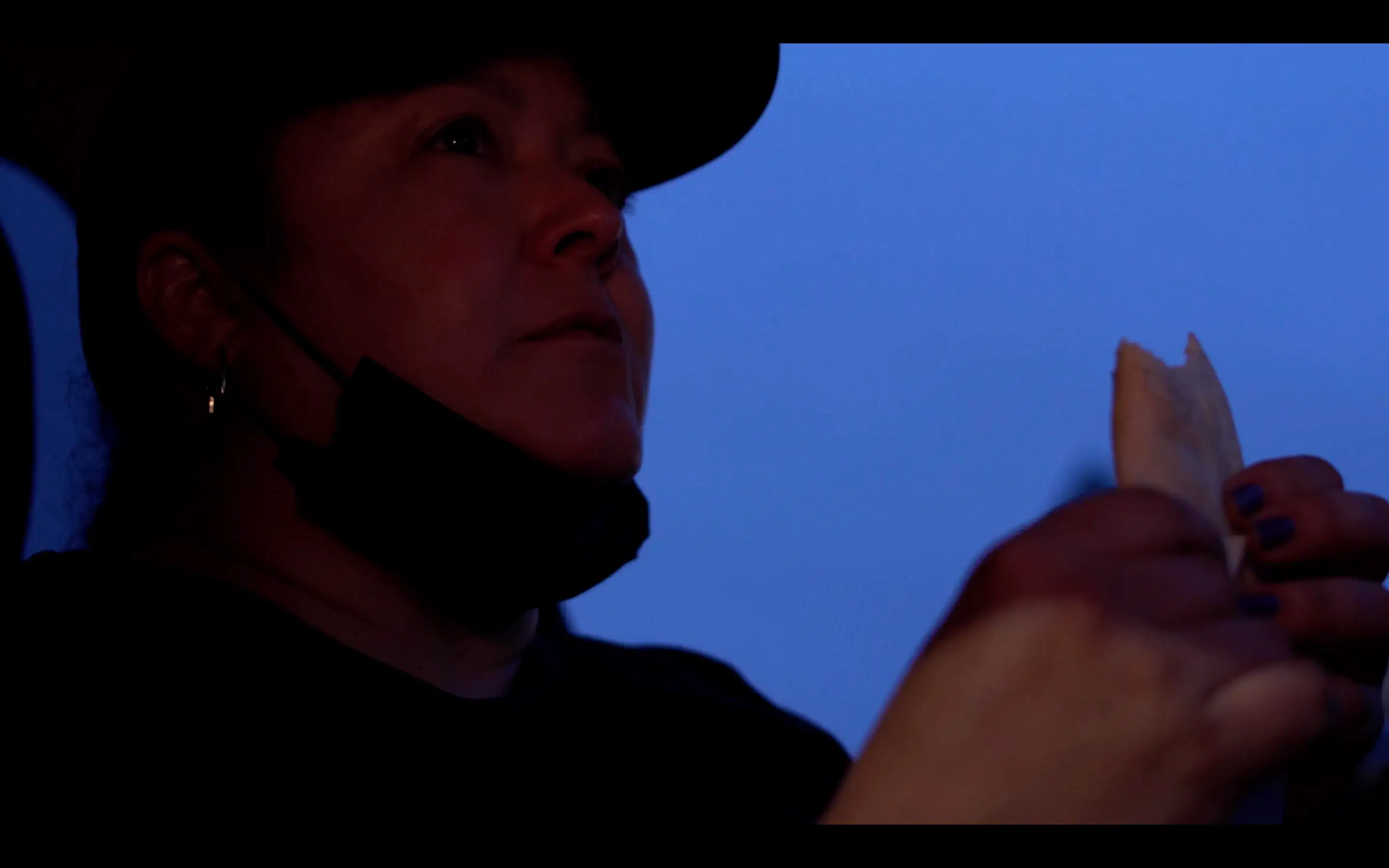 Woman sitting in front seat of car against dark blue sky 