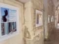 At the entrance of the Romanesque cloister of Saint-Paul de Mausole, several works hang in white frames on a stone wall. The first framed piece is a poster for the exhibition, which is titled "Transitions."