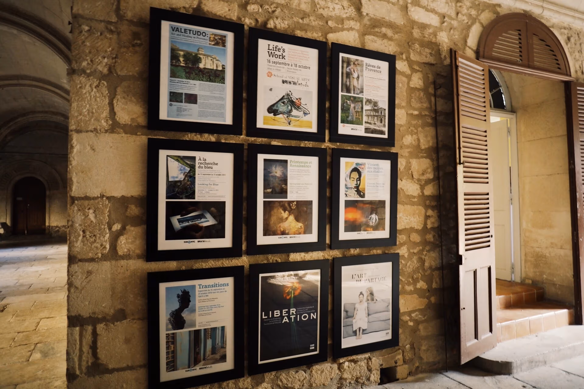 Nine posters for previous exhibitions hang on a stone wall at the Saint-Paul de Mausole.