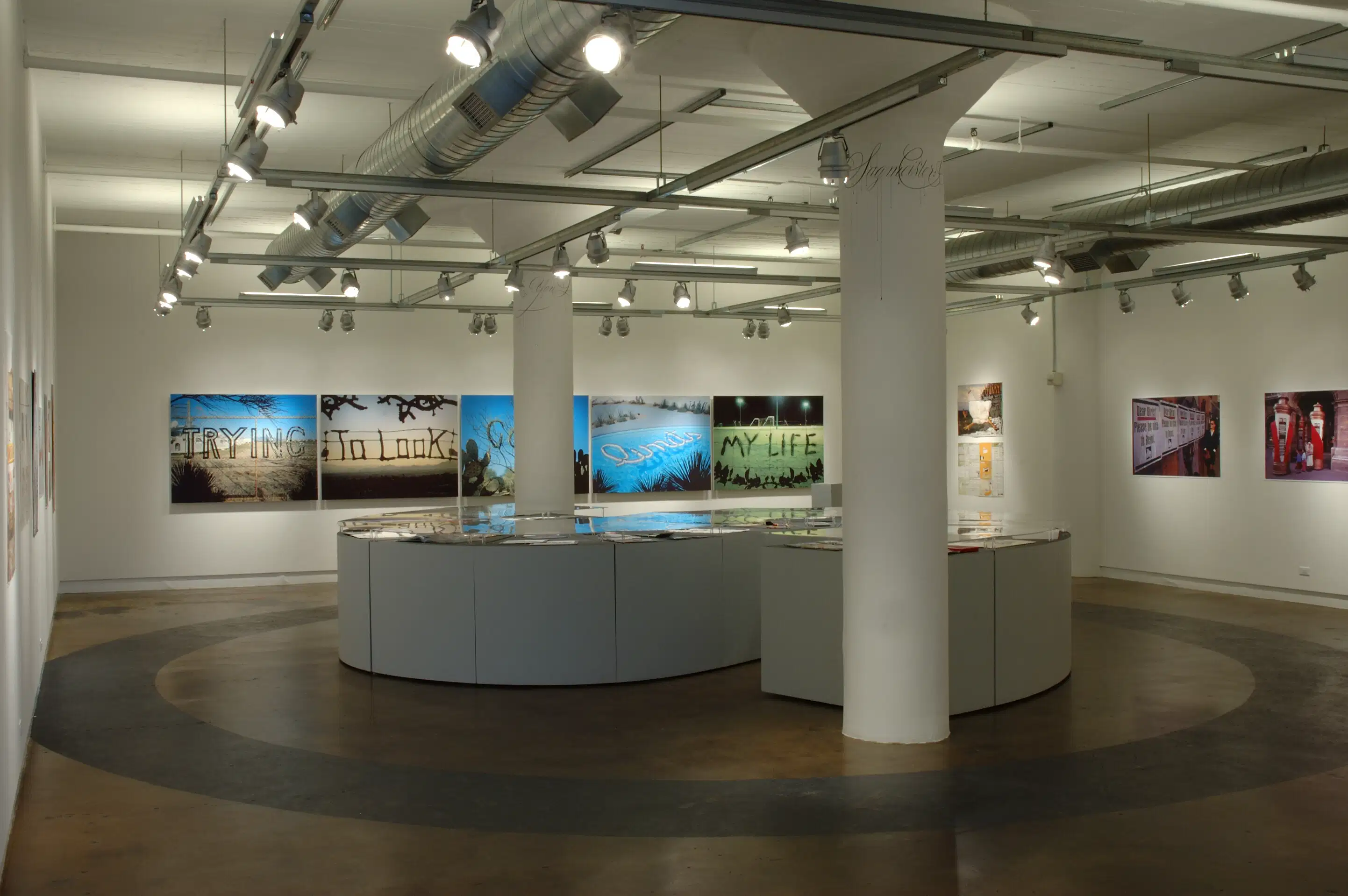 A photograph of an art gallery with art featuring words.