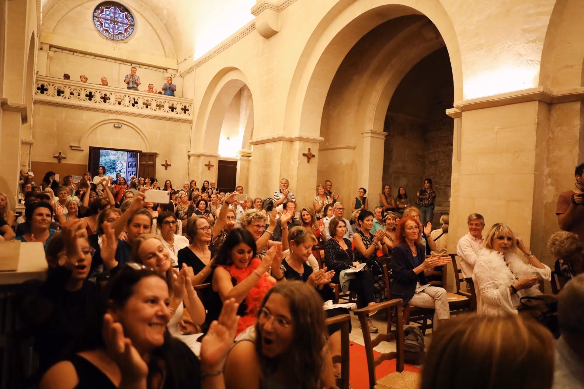 A large audience claps and cheers inside of the Saint-Paul de Mausole as they watch the performance.