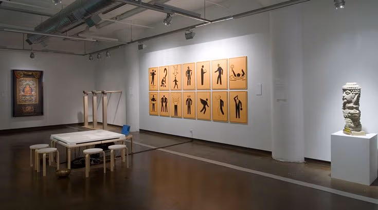 Several paintings wall mounted in an art exhibit surrounded