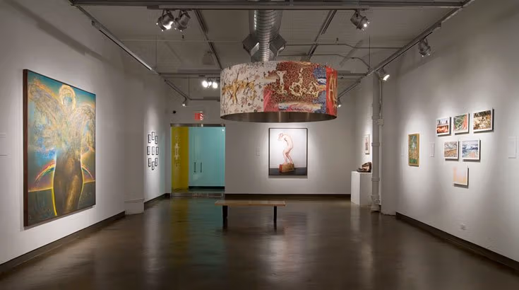 A large room with art paintings on the walls and an art light fixture.