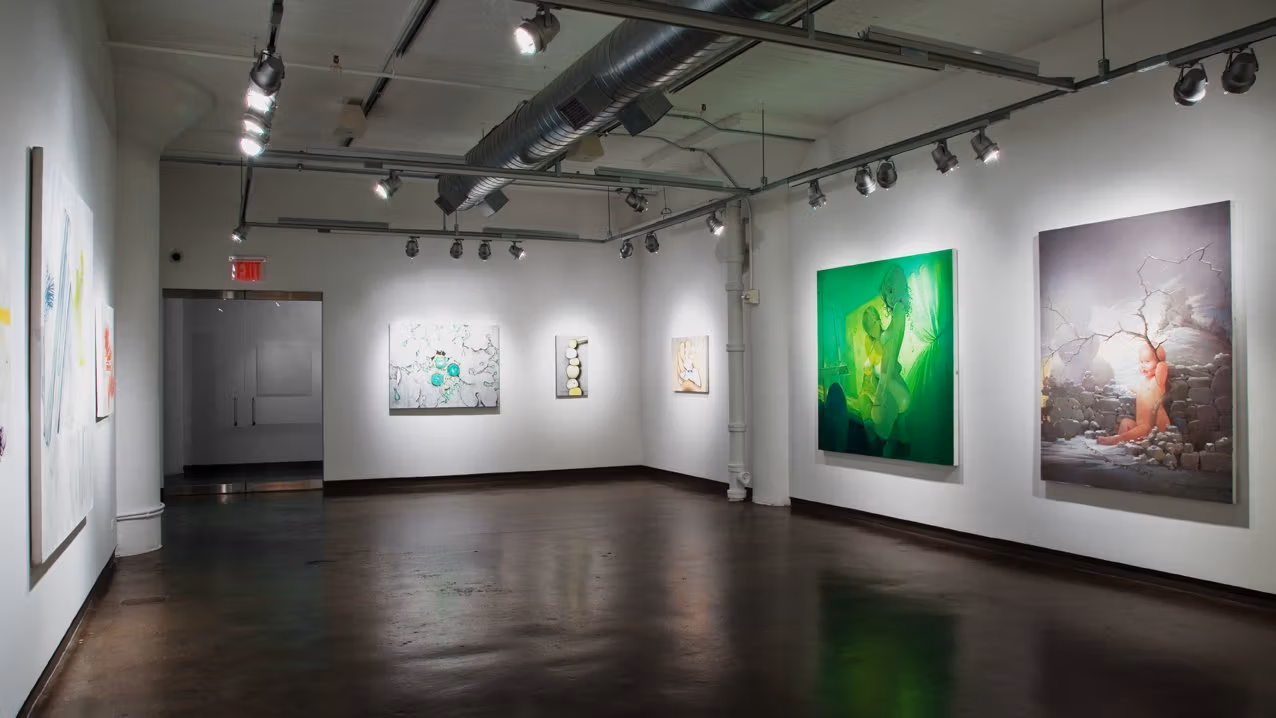 Exhibition photograph of “Between Picture and Viewer" showing three walls of gallery. On the left are three barely visible paintings, in the center is an exit and two paintings to its right, and on the far right is a wall with three paintings.