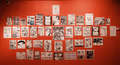 Photograph of red gallery wall containing a large group of pen and ink drawings.