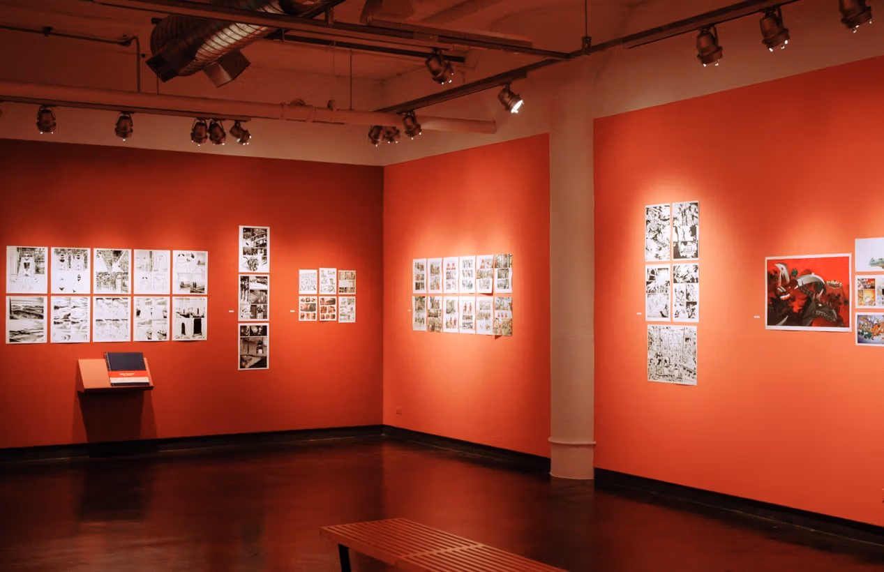 Photograph of red gallery walls containing groupings of pen and ink drawings.