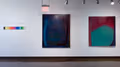 On the left is the exhibition title on gallery wall, with a printed vinyl "bar" of fourteen segmented colors of the rainbow in a horizontal line below it. To the right are two large (approximately 6 feet x 4 feet) abstract paintings using lines and fields of color to create minimalist compositions.