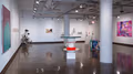 Entry view of first of four spaces at SVA Chelsea Gallery, showing artwork on three walls and several large sculptures sitting on the floor.