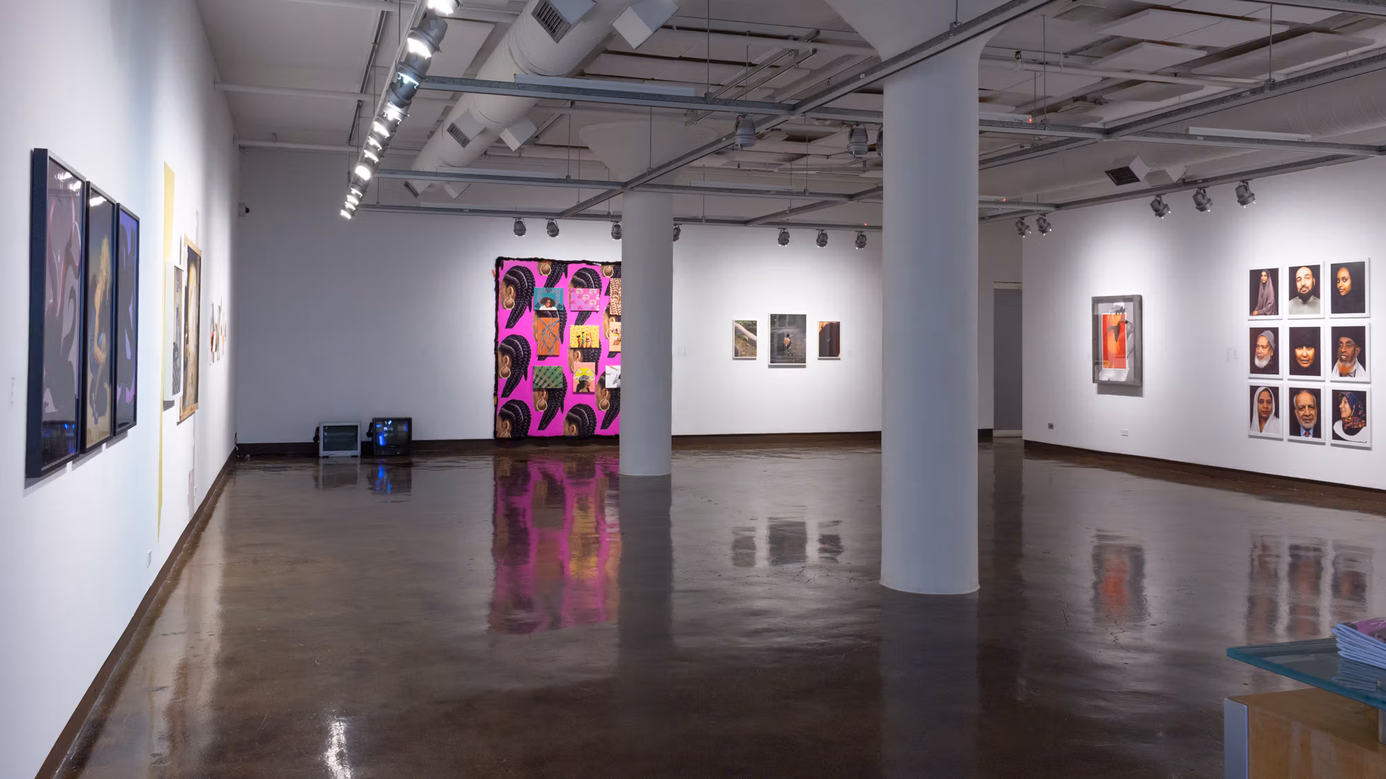 Installation shot of artwork as one enters SVA Chelsea Gallery, showing a variety of photographic and video artworks across three walls.