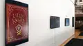 Four monitors on a white wall, the furthest to the left is vertical and shows a book cover for "The Little Knight" in red and gold.