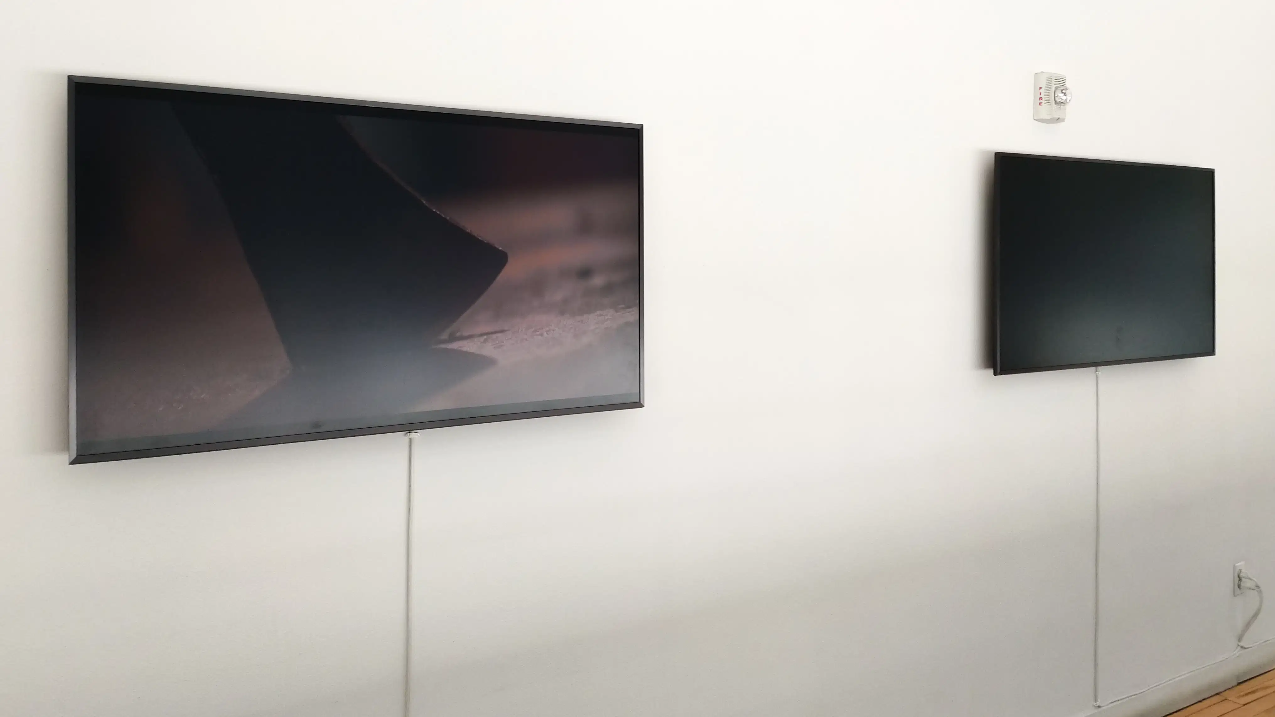 Two monitors on a white wall