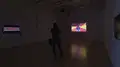 Multiple views of SVA Flatiron Gallery. There are three monitors playing various videos on the wall and an interactive projection. 
