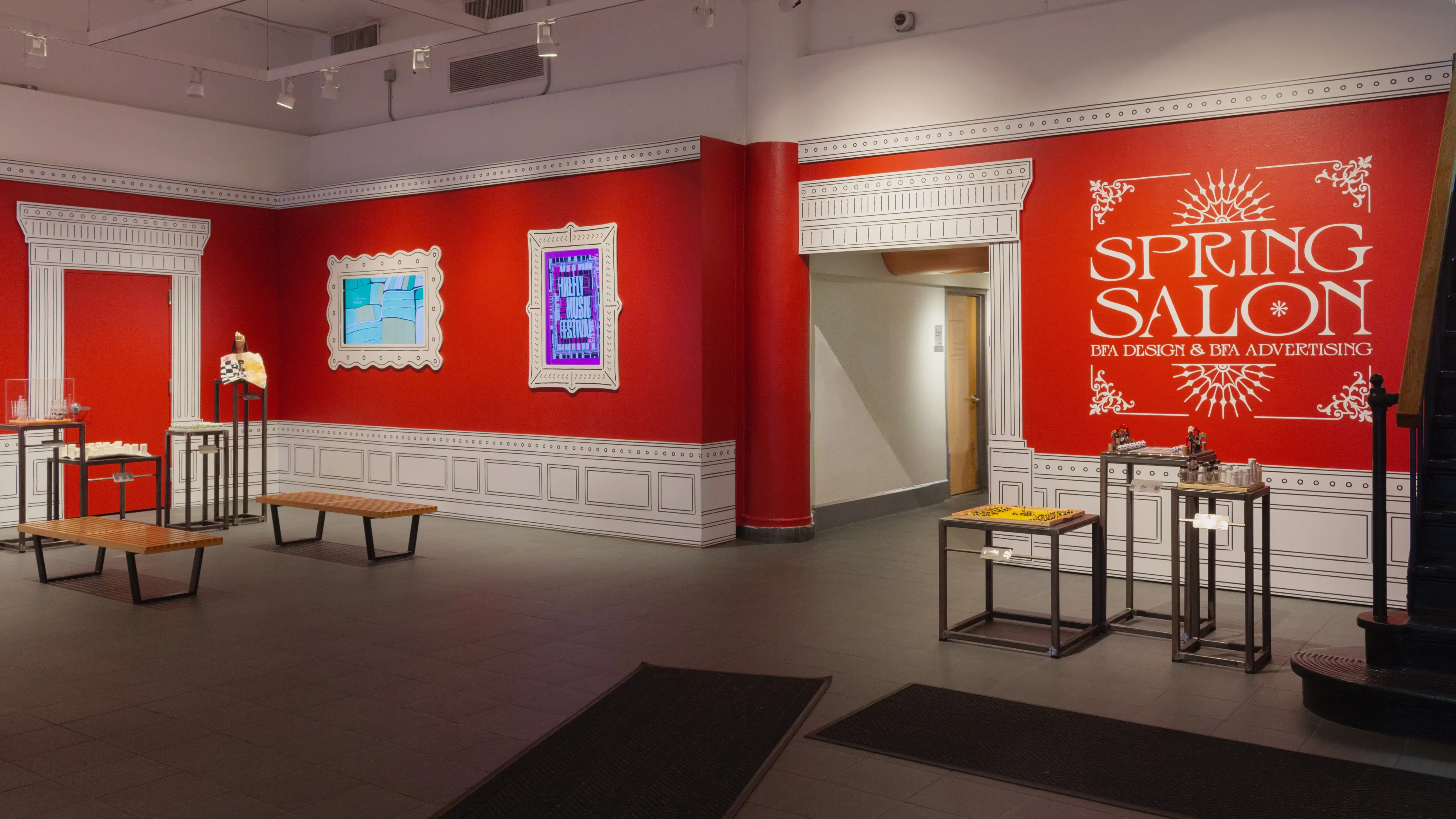 Multiple views of SVA Gramercy Gallery. The lobby is pained red with "Spring Salon" in ornate lettering and the gallery is painted blue. There are monitors in ornate frames playing student work through the gallery. In the center of the lobby and gallery are metal pedestals with student work on them. 