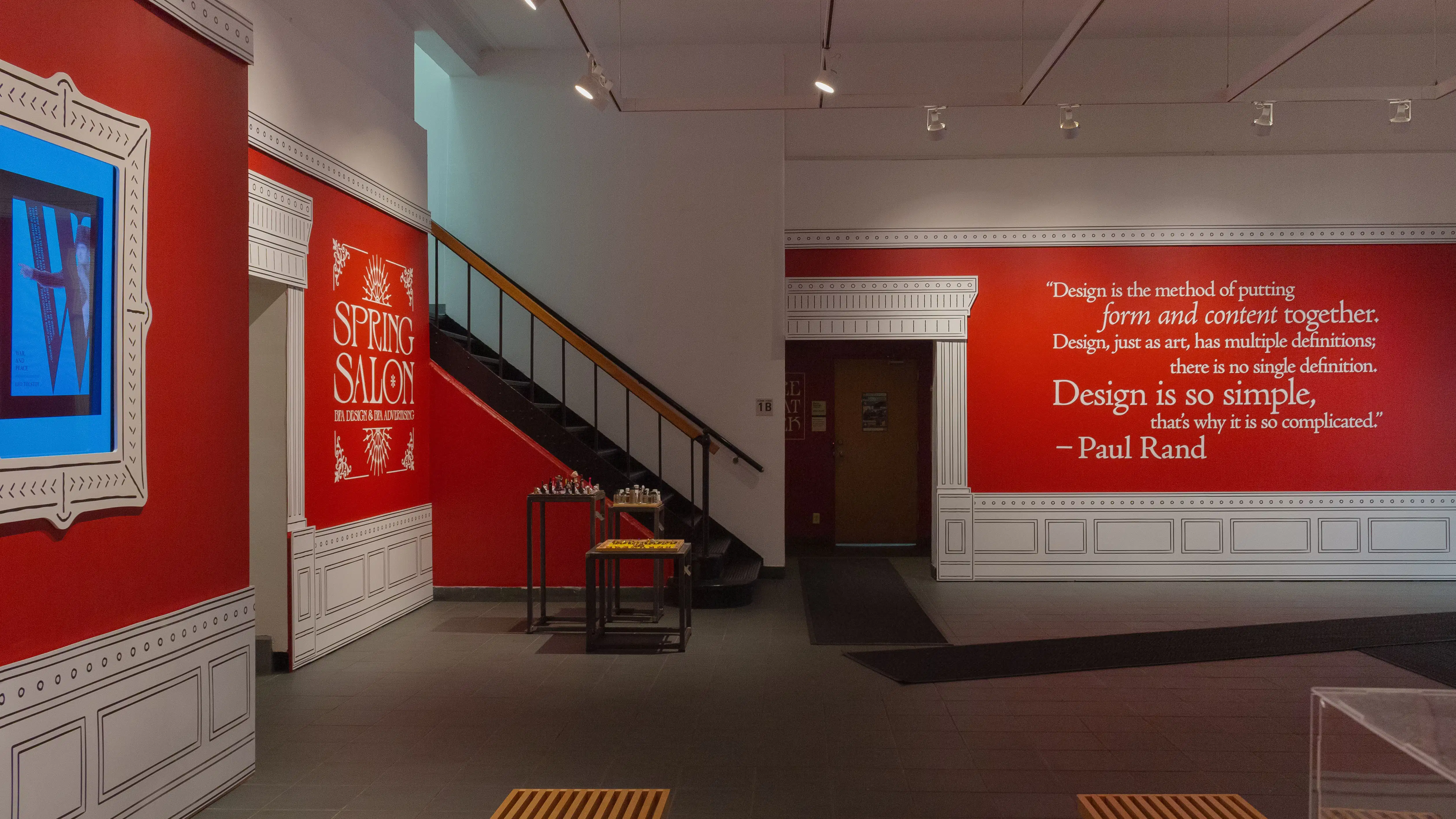 Multiple views of SVA Gramercy Gallery. The lobby is pained red with "Spring Salon" in ornate lettering and the gallery is painted blue. There are monitors in ornate frames playing student work through the gallery. In the center of the lobby and gallery are metal pedestals with student work on them. 
