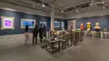 Multiple views of SVA Gramercy Gallery. The lobby is pained red with "Spring Salon" in ornate lettering and the gallery is painted blue. There are monitors in ornate frames playing student work through the gallery. In the center of the lobby and gallery are metal pedestals with student work on them. 