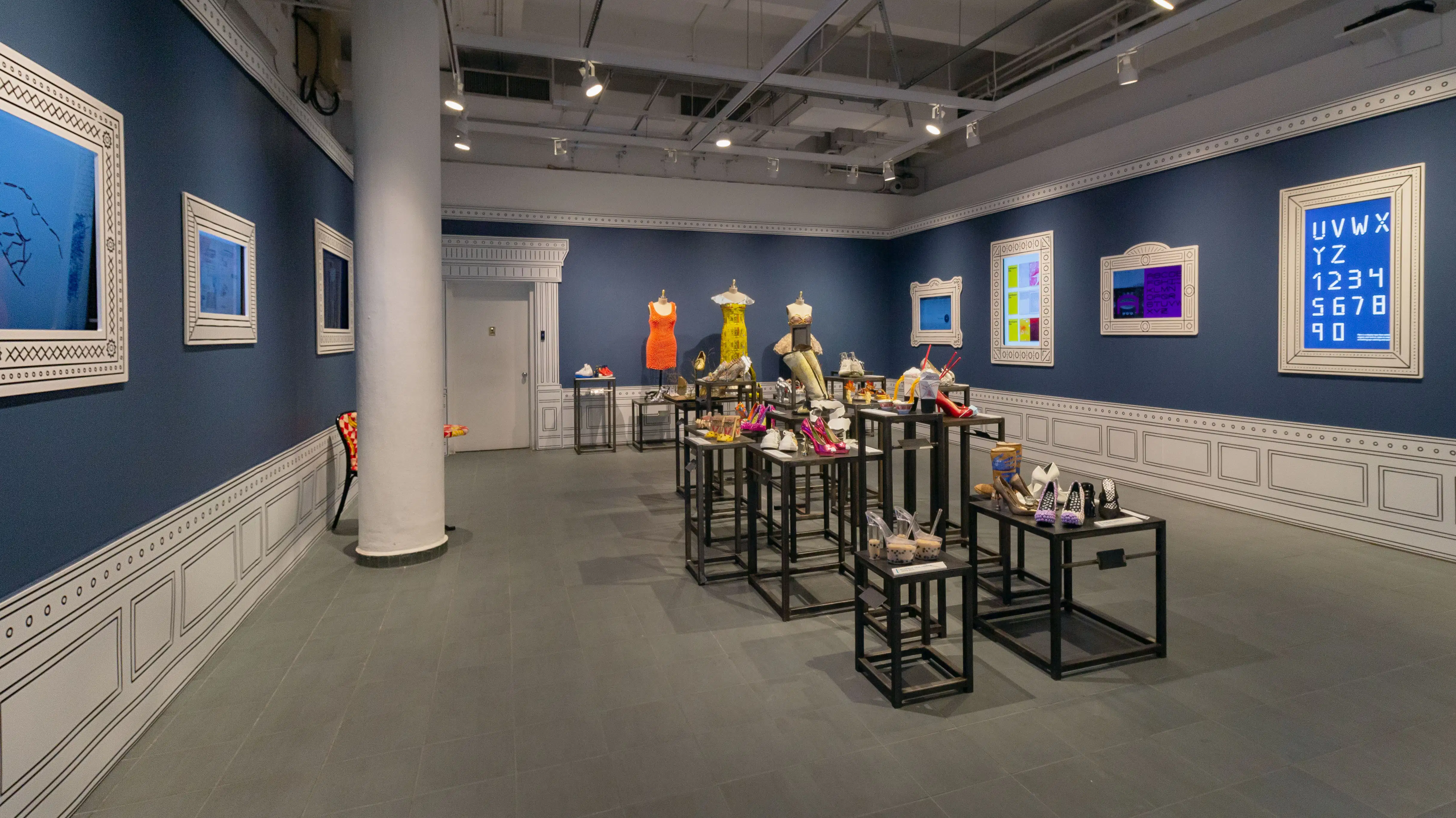 Multiple views of SVA Gramercy Gallery. The lobby is pained red with "Spring Salon" in ornate lettering and the gallery is painted blue. There are monitors in ornate frames playing student work through the gallery. In the center of the lobby and gallery are metal pedestals with student work on them. 