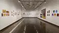 Multiple views of SVA Chelsea Gallery. There is illustrations and paintings hung on the walls. There are multiple shelves throughout the gallery with books places on them.