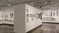 Multiple views of SVA Chelsea Gallery. There is illustrations and paintings hung on the walls. There are multiple shelves throughout the gallery with books places on them.