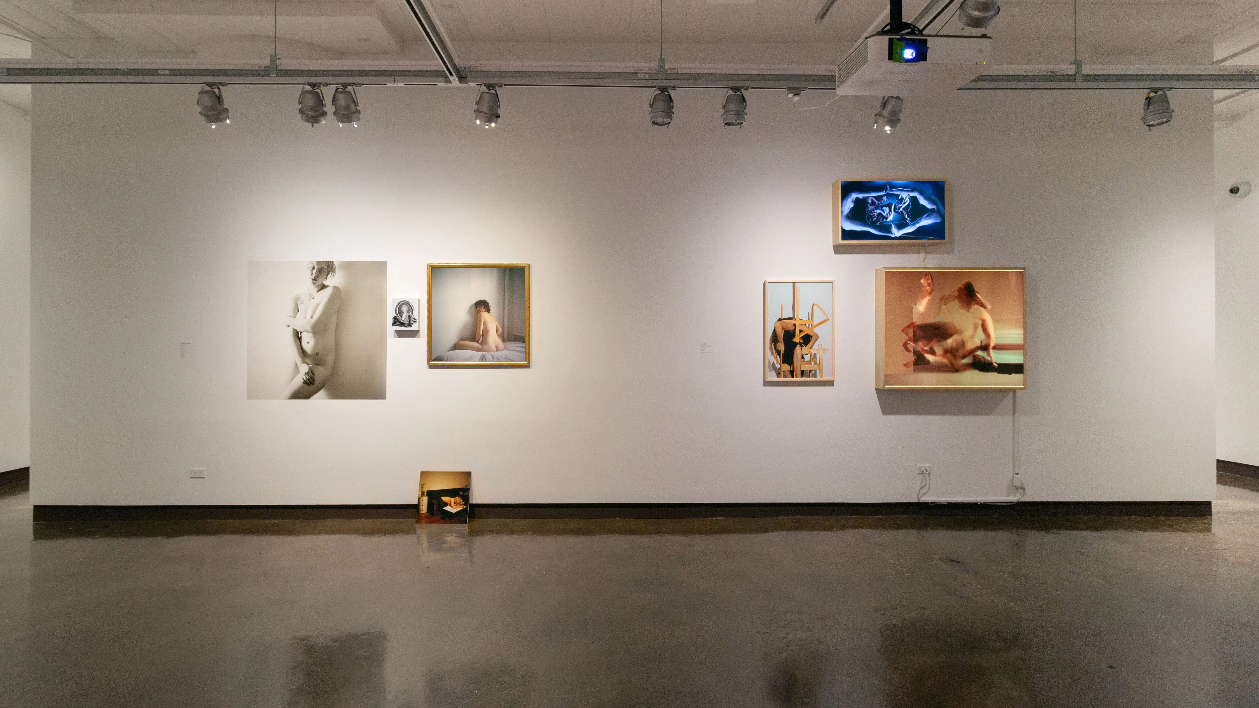 Multiple views of SVA Chelsea Gallery. There are photographs hung on the wall, installations and projections throughout the gallery. 