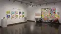 Multiple views of SVA Chelsea Gallery. There are illustrations, monitors, and paintings hung on the walls. Shelves have posters, books, CDs and artist take-aways.