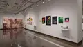 Multiple views of SVA Chelsea Gallery. There are illustrations, monitors, and paintings hung on the walls. Shelves have posters, books, CDs and artist take-aways.