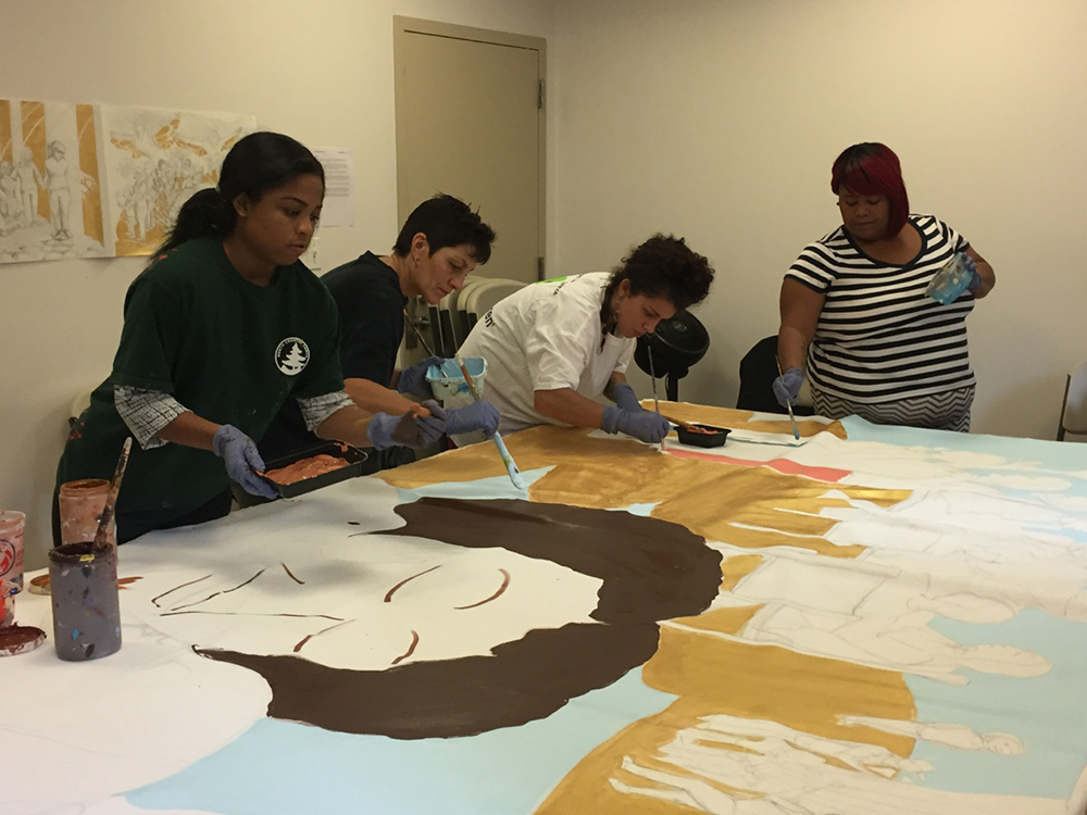 A group of students working together to paint a large mural. The mural has very little details of humans.