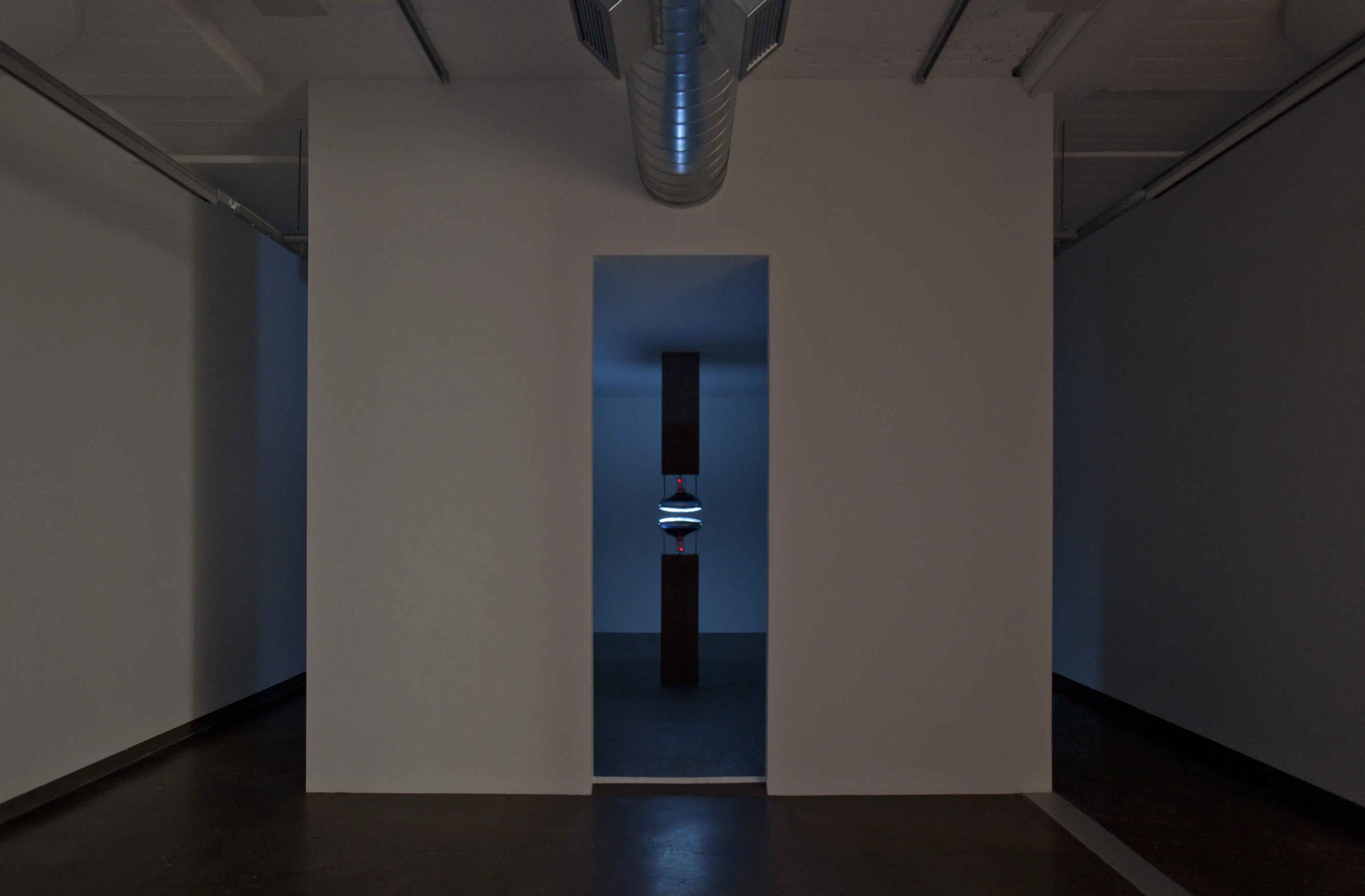 A simple art showcase in a room with two glowing objects.