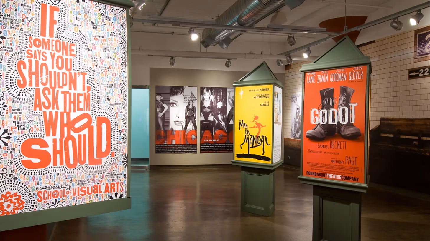 Photograph from inside SVA Chelsea Gallery with advertising graphics hung on walls.