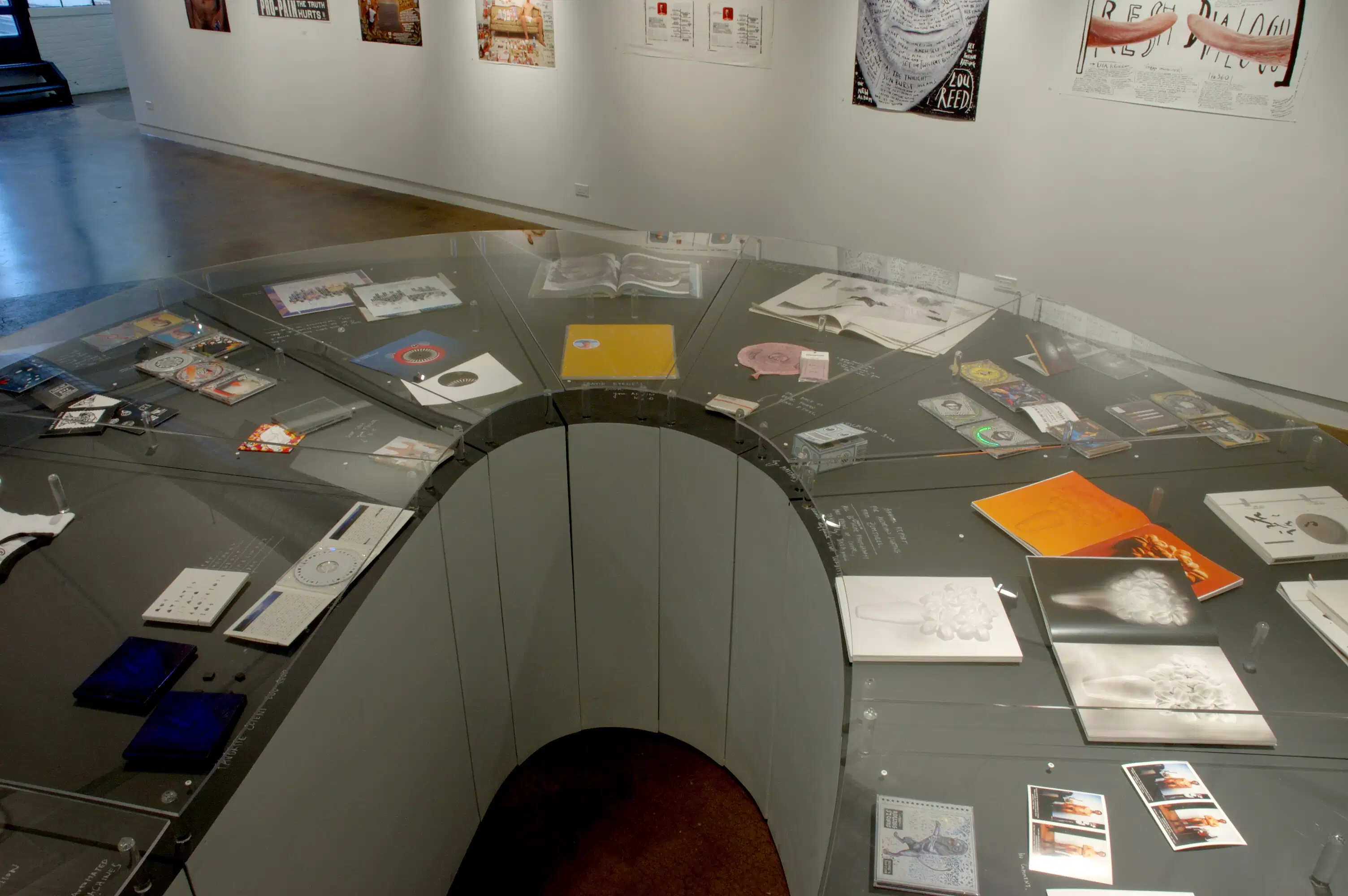 A showcase with different photographs, CD's, and other objects inside of it.