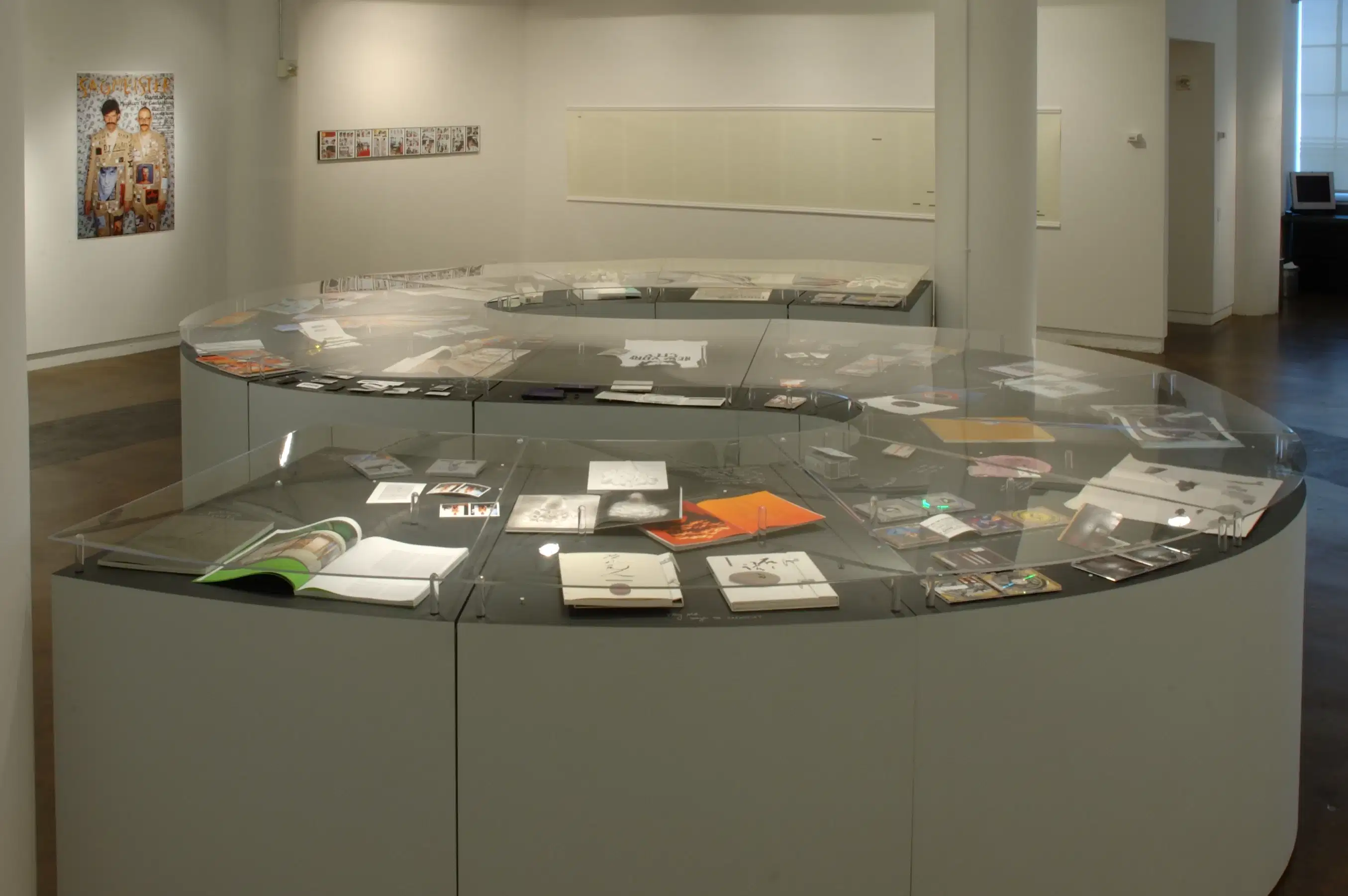A curved counter, in the shape of an "S," displays books and prints within it. 