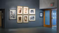 Photograph from inside lobby gallery of Visual Arts Museum with exhibition text, "Time Line: Sheila Metzner" on the wall to the far right, on the left are several framed photographs of nudes and flowers.