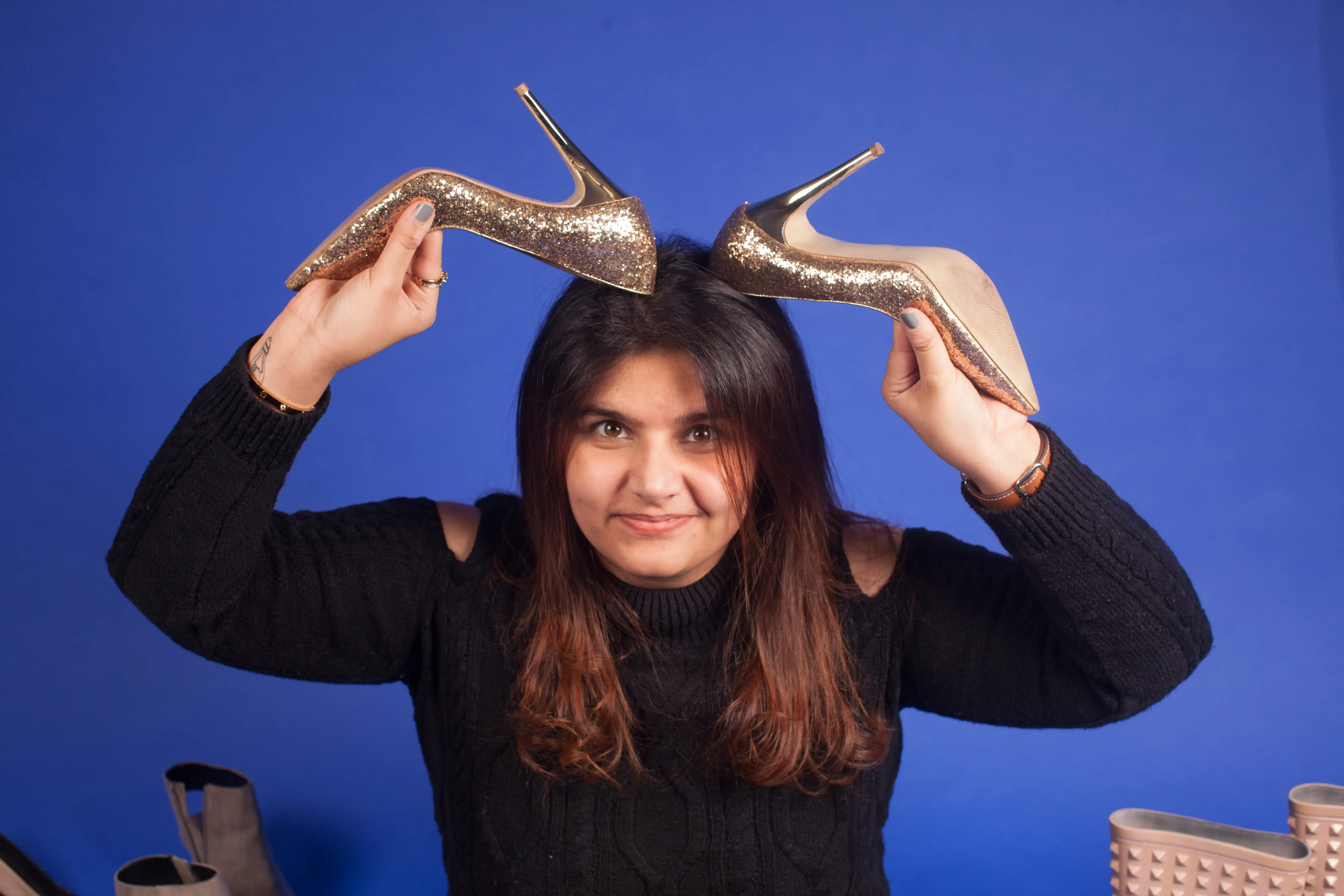 Image of lady in black with red hair making horns with her high heels.