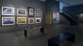 Photograph from inside lobby gallery of Visual Arts Museum, with framed photographs of buildings, flowers, celebrities, and family portraits by Sheila Metzner.